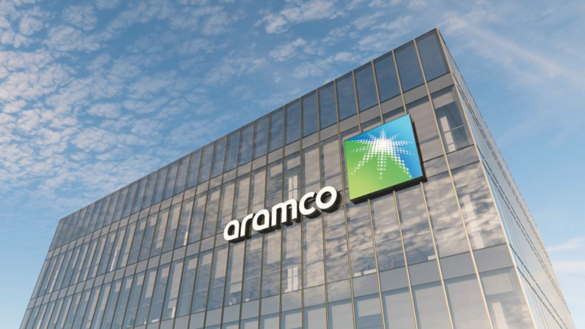 Aramco office building exterior with company logo on glass facade under blue sky.