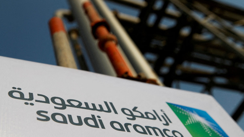 Saudi Aramco branding sign with industrial pipes in the background